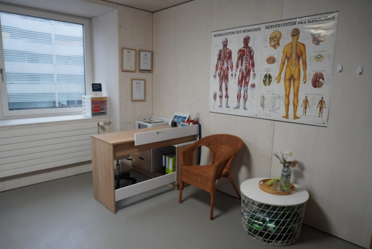 Beratungsplatz mit Schreibtisch und Anatomiepostern in der Praxis